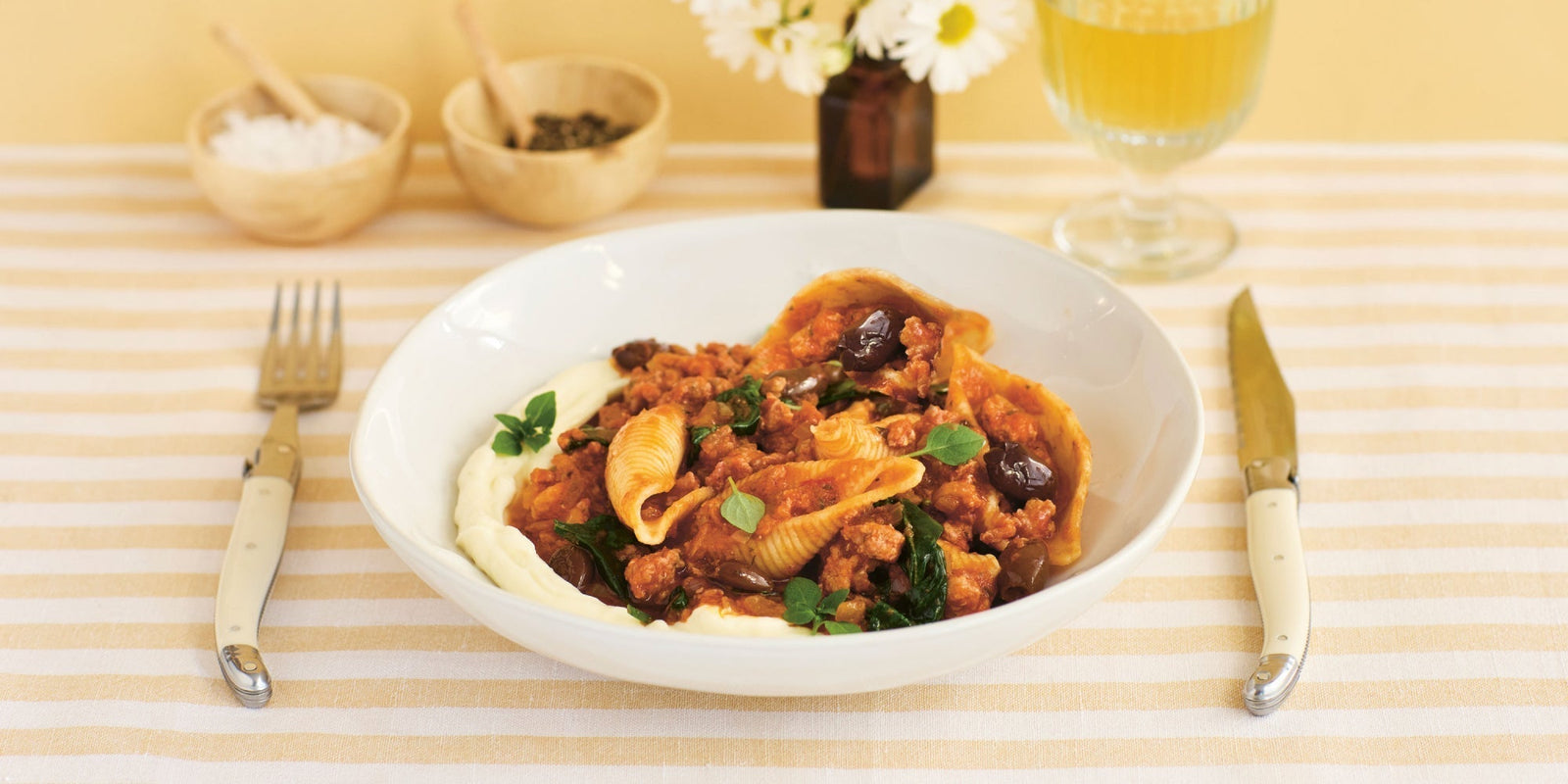 A bowl of pasta shells with a rich tomato sauce on a creamy bed of ricotta